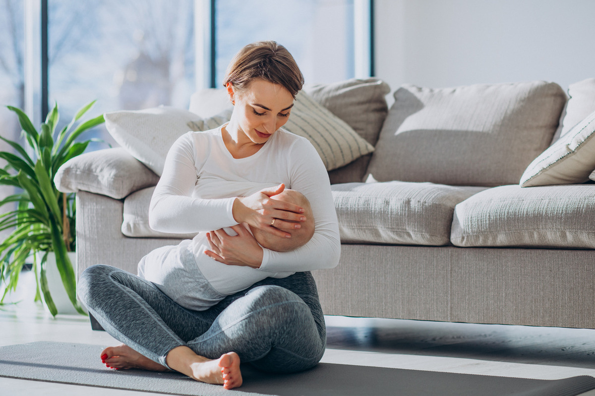 Mother breastfeeding her baby on the floor in front of a sofa, Lactation Consultant in Pune